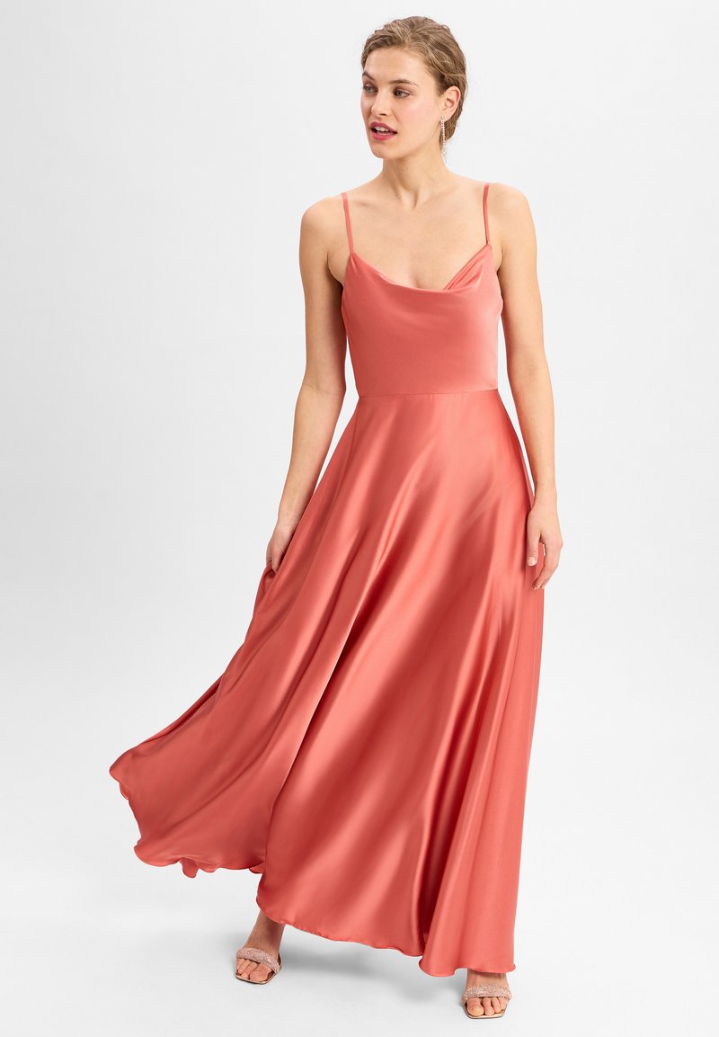 Korallefarbendes Satin-Maxikleid mit dünnen Spaghettiträgern und Karree-Ausschnitt, fließendem Rock und glatter Textur, kombiniert mit Riemchensandalen.