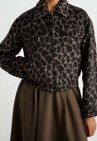 Jaguarprickig jacka med fuskpälsstruktur, dragkedjestängning och två framfickor. Kort design med krage. Bruna och beige toner.