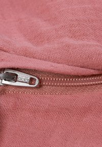Pink textured fabric with a visible metal zipper. The weave indicates a linen-like material, showcasing a soft, slight sheen.