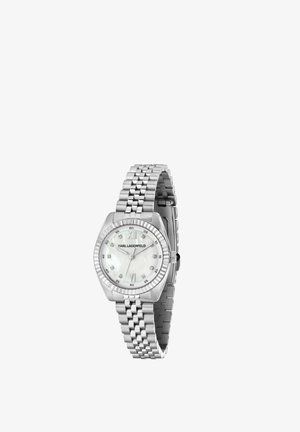 Montre-bracelet argentée Karl Lagerfeld avec bracelet en maillons métalliques, cadran blanc, chiffres romains à 12 et 6 heures, et index d’heures en cristal.