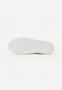 Suola di sneaker bianca in gomma con un motivo testurizzato caratterizzato da scanalature e il logo stampato 'HUGO' chiaramente visibile.