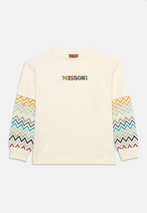 Cămașă crem cu mâneci lungi și mâneci cu model zigzag multicolor și cuvântul "MISSONI" în culori asortate pe piept.