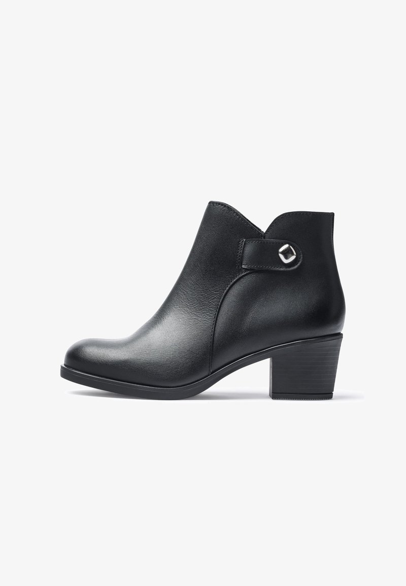 Botines de cuero negro con punta redondeada, tacón bloque de altura media y un pequeño acento plateado en la correa lateral. Textura suave.