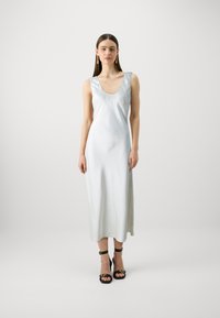 Rochie midi fără mâneci din satin, de culoare albastră deschisă, cu decolteu rotund și textura netedă. Pur și simplu cu sandale negre cu curele și accente aurii.