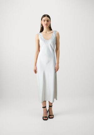 Robe midi sans manches en satin bleu clair avec un décolleté en arrondi et une texture lisse. Portée avec des sandales noires à lanières avec des accents dorés.