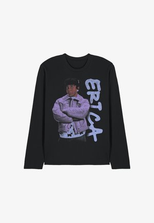 Schwarzes Langarmshirt mit Grafik einer Frau in lila Jacke, die die Arme verschränkt hat, daneben das Wort „ERICA“ in großen, stilisierten hellvioletten Buchstaben.