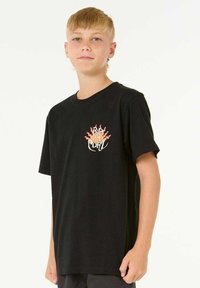 T-shirt en coton noir à manches courtes, col rond, avec un graphique coloré de mains et de flammes sur la partie gauche de la poitrine.