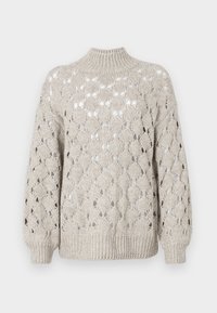 Strikkegenser i lys beige med et løst, teksturert design som har et mønster av åpen arbeidsdiamantformer. Høy krage og ribbede mansjetter.