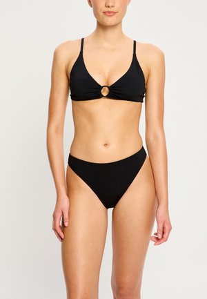 Schwarzes Bikinioberteil mit einem dreieckigen Schnitt, zentralem Metallring und dünnen verstellbaren Trägern. Der Slip ist im niedrigen Schnitt und zeichnet sich durch ein einfaches Design aus.