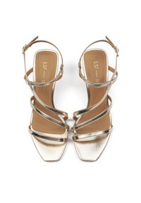 Goldene Riemchen-High-Heel-Sandalen mit quadratischer Zehenpartie, ausgestattet mit metallischen Riemen und einem braunen Fußbett mitprägierter Logo-Detail.