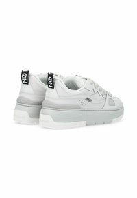 Sneakers bianchi con superficie texture, linguetta imbottita e accenti grigi. Presentano una suola spessa e occhielli neri con dettagli del logo.
