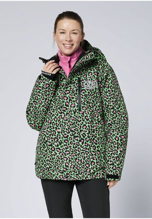 Grün-pinke Steppjacke mit Leopardenmuster, Kapuze, Reißverschlusstaschen und elastischen Bündchen, getragen über einem pinken Oberteil.