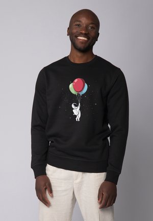 Sweatshirt noir avec un graphique d'astronaute tenant des ballons colorés, des coutures distinctes et une coupe classique. Texture lisse avec un col rond.