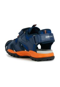 Sandales bleues et orange avec des sangles ajustables, une tige en maille respirante et une semelle extérieure en caoutchouc texturé pour une meilleure adhérence. Marque Geox visible.