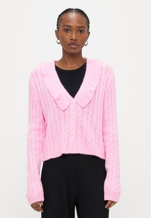 Ροζ πλεκτή ζακέτα με φαρδύ γιακά, υφή καναλιού πλέξης, και μακριά μανίκια, με κομψή εφαρμογή cropped και κλείσιμο με πέντε κουμπιά.