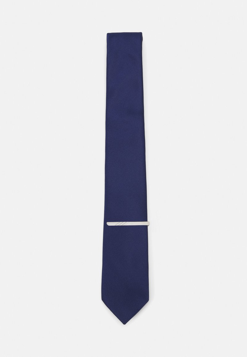 Cravate en soie bleu marine avec une texture lisse et une pointe effilée, ornée d'un clip en argent au milieu pour un détail supplémentaire.