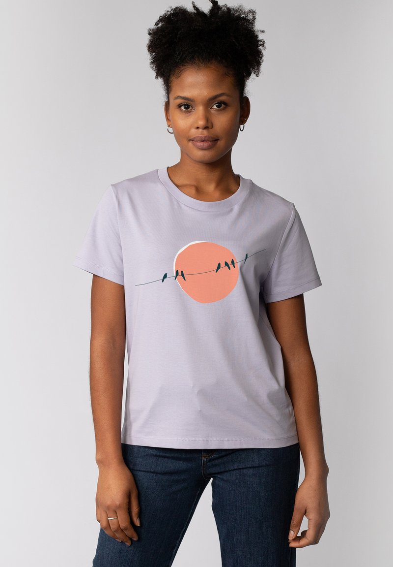 Helle lila Baumwoll-T-Shirt mit Rundhalsausschnitt, das ein grafisches Design mit einer großen orangefarbenen Sonne und Vögeln auf einer Leitung zeigt. Kurzärmlig.