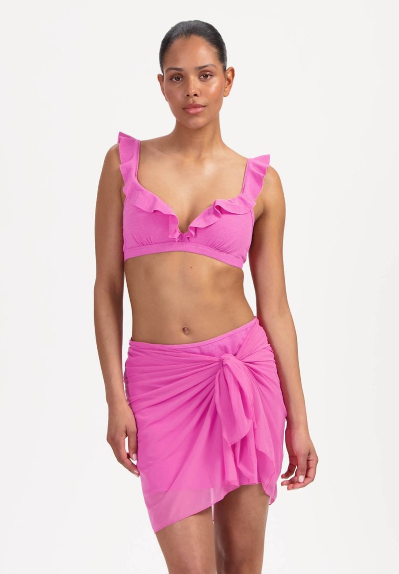 Pinkes Bikinioberteil mit gerafften Kanten und einem passenden, durchsichtigen rosa Wickelrock, der an der Taille gebunden ist. Glatte Textur und figurbetonte Silhouette.