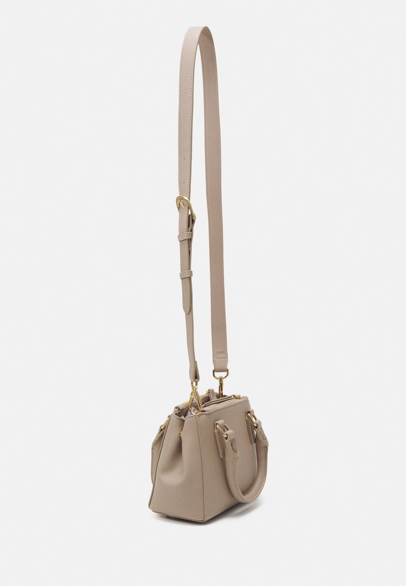 Sac à main en cuir beige avec une forme structurée, accents en matériel doré, deux poignées courtes et une bandoulière amovible et réglable.