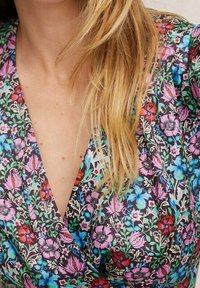 Blumenmusterkleid mit dunklem Hintergrund und bunten Blumen in Rosa, Blau und Rot; weicher Stoff und tiefem V-Ausschnitt.