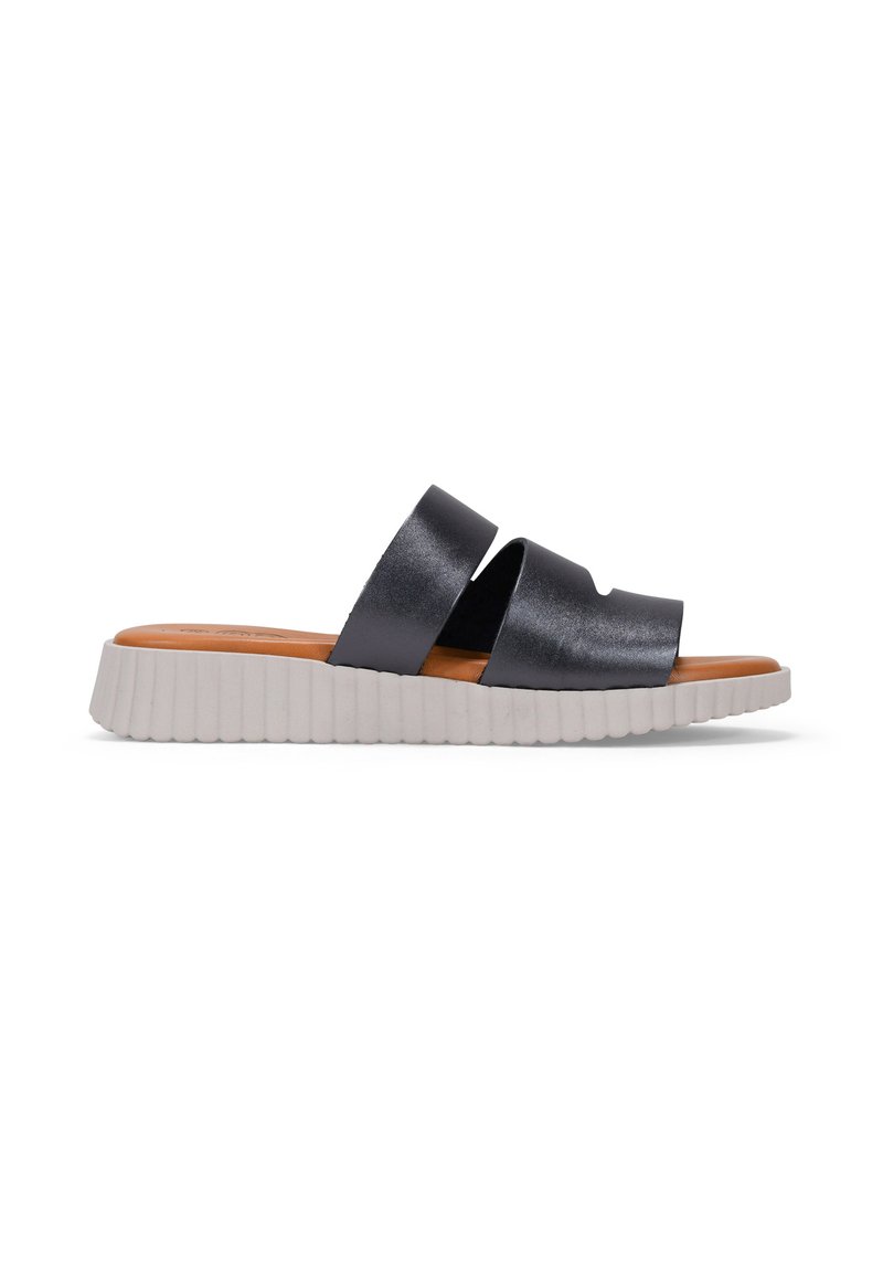 Sandalia deslizante negra y mate con dos correas anchas. Presenta una suela blanca flexible y estriada, y una plantilla marrón. Diseño minimalista y construcción ligera.