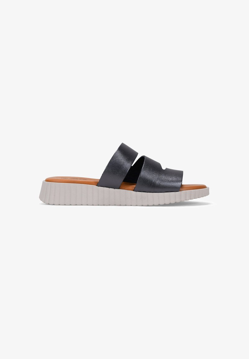 Sandalia deslizante negra y mate con dos correas anchas. Presenta una suela blanca flexible y estriada, y una plantilla marrón. Diseño minimalista y construcción ligera.