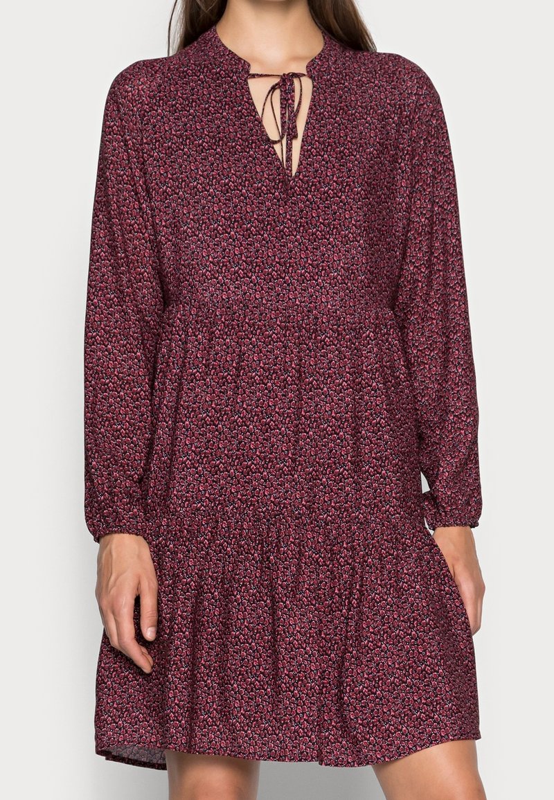 Mörkröd blommig klänning med långa ärmar, rynkad midja och nyckelhålshalsringning med bindsnörning. Lättviktsmaterial med en flödande textur.