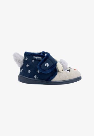 Zapatillas infantiles de felpa en azul marino y beige con diseño de huella, con una correa de gancho y bucle y orejas decorativas grises.