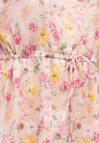 Φλοράλ φόρεμα σε απαλό ροζ ύφασμα, με πολύχρωμα λουλούδια, στρογγυλή μέση με δέσιμο και ελαφρύ, υφασμένο υλικό.