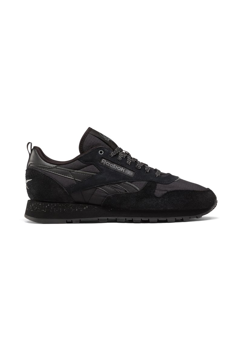 Czarne sneakersy Reebok z mieszanym materiałem i zamszową cholewką, szare sznurówki, logo z boku oraz nakrapiana teksturowana podeszwa, skierowane w lewo na białym tle.