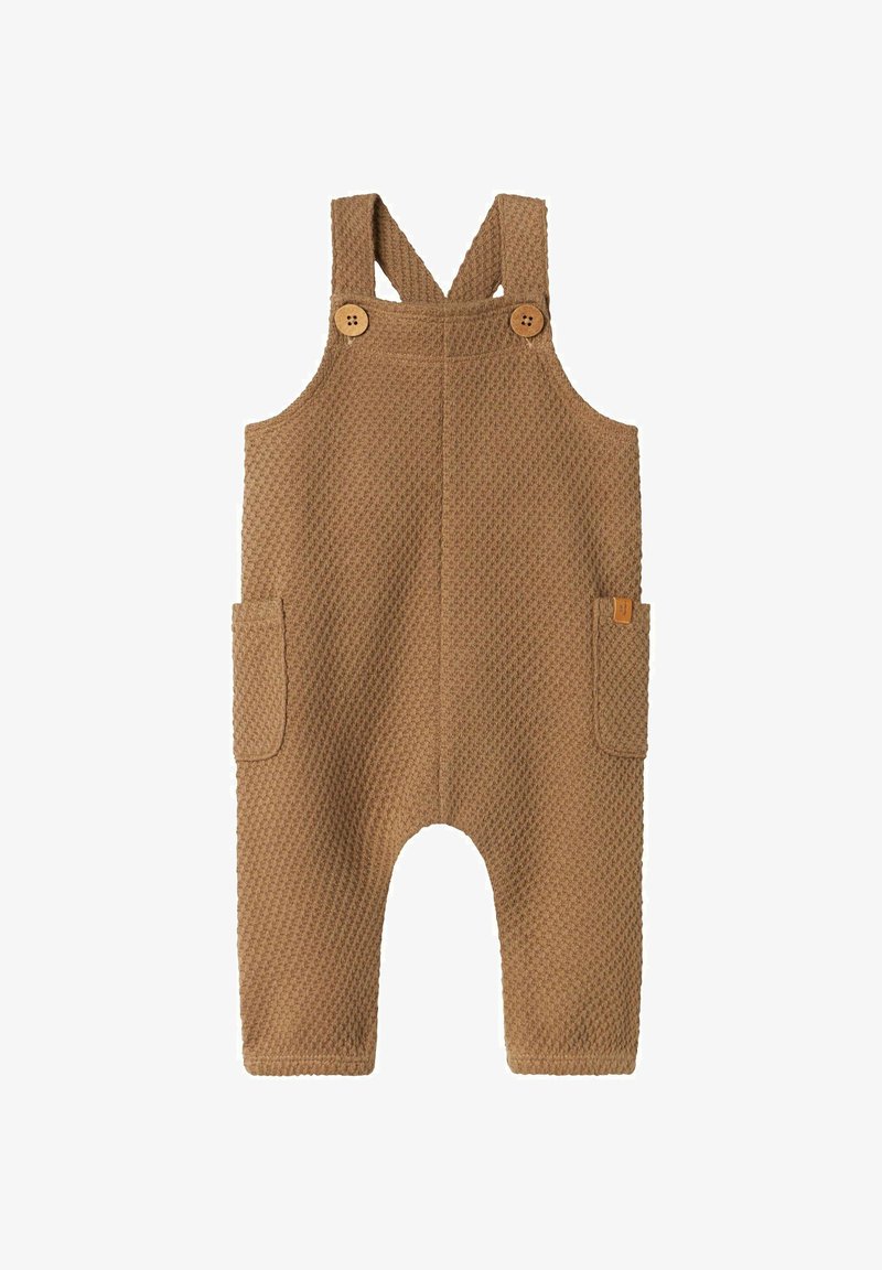 Bruna texturerade babybyxor med två trärknappar på axelremmarna och fickor på båda sidor, liggande platt på vit bakgrund.