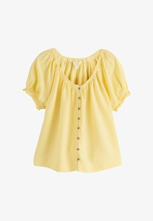 Blouse en lin jaune avec un décolleté en U, des manches bouffantes et une patte de boutonnage à l'avant. Présente des détails froncés aux manches et au niveau du col.