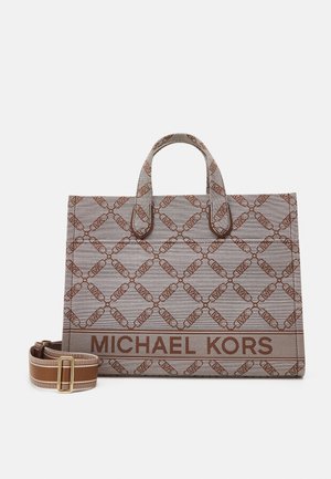 Bruine en beige gevlekte Michael Kors schoudertas met twee handvatten en een afneembare gestreepte schouderriem op een witte achtergrond.