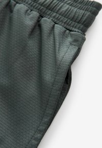 Mørkegrønne athletic shorts lavet af tekstureret stof med elastisk talje. Har subtile linjemønstre og sidelommer.