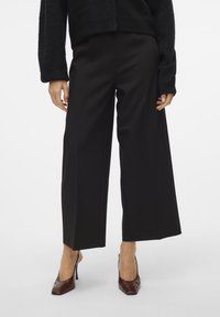 Pantalons larges noirs en tissu lisse, dotés d'une coupe ajustée et d'une silhouette droite épurée qui arrive à la cheville.