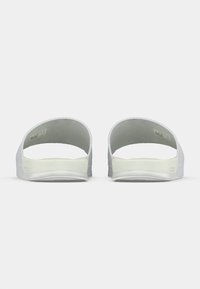 Λευκά σανδάλια τύπου slide, που βλέπουμε από πίσω, με υφή στην σόλα και φαρδιές λουρίδες επάνω.