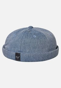 Gorra de denim azul con parte superior redondeada, borde con visera y un pequeño logo bordado en el lateral. Tela texturizada con detalles de costura visibles.