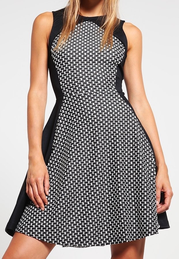 Robe noir et blanc avec un haut tissé texturé et une jupe noire unie, dotée d'un corsage ajusté et d'un ourlet évasé.