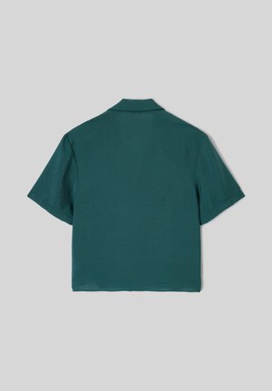 Chemise bleu canard à manches courtes avec une coupe ample et un col, vue de dos sur un fond gris neutre.