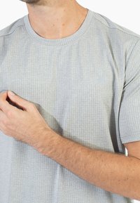 Světle šedé tričko s krátkým rukávem vyrobené z texturované, žebrované látky, s kulatým výstřihem a jemným logem na hrudi.