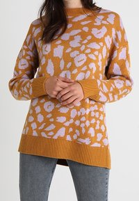 Stickad tröja i senapsgul med ljuslavendel abstrakt leopardmönster, med ribbade ärmslut och nederkant, avslappnad passform och mjuk textur.