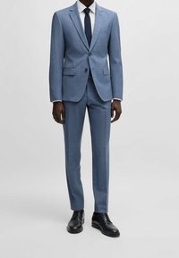  Lichtblauw pak van een gestructureerde stof, met een single-breasted jasje met een gesneden revers, gecombineerd met slim-fit broek en zwarte schoenen.