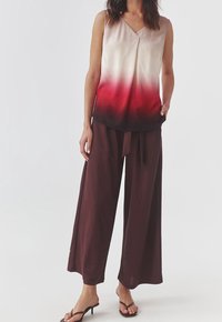 Top sans manches en satin avec un dégradé allant du beige clair au rouge profond, associé à un pantalon large marron foncé avec une taille nouée.