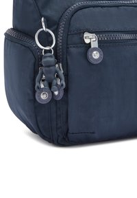 Zaino in nylon blu navy con una texture liscia, dotato di una cerniera argentata, tasti rotondi e un portachiavi a forma di scimmia come decorazione.