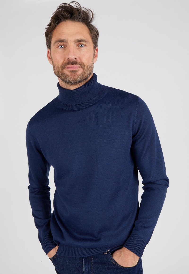 Suéter de cuello alto de color azul marino hecho de una suave tela de punto, con mangas largas y dobladillo y puños acanalados. Diseño simple y limpio.