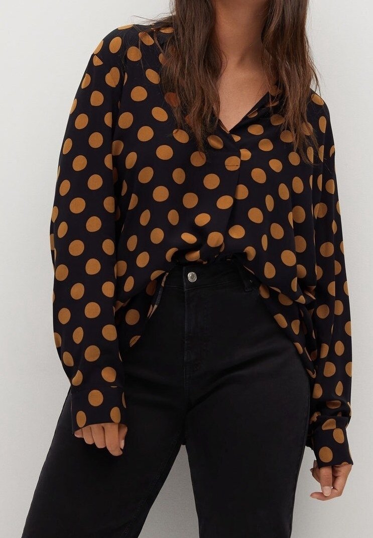 Mustapohjainen pitkähihainen paita, jossa on suuria ruskeita pilkkuja, V-mallinen kaula-aukko ja rento leikkaus. Yhdistetty korkeavyötaisien mustien housujen kanssa.