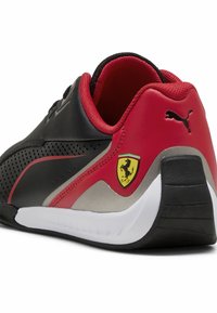 Mustikkainen ja punainen lenkkarit, joissa on teksturoitu päällinen, kaareva muoto, Puma-logo ja Ferrari-embleemi kantapäässä. Kumikenkäntä, jossa on valkoinen välipohja.