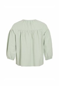 Blouse vert clair avec un dos froncé, coupe décontractée, col rond et manches trois-quarts. Fabriquée en tissu doux et texturé.
