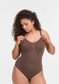 Body in tessuto leggero color marrone con spalline regolabili, design senza cuciture e texture morbida. Presenta dettagli di contorno sottili sul davanti.