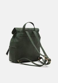 Green faux leather backpack with a fold-over flap, top handle, adjustable shoulder straps, and a side pocket. Features gold-colored hardware.